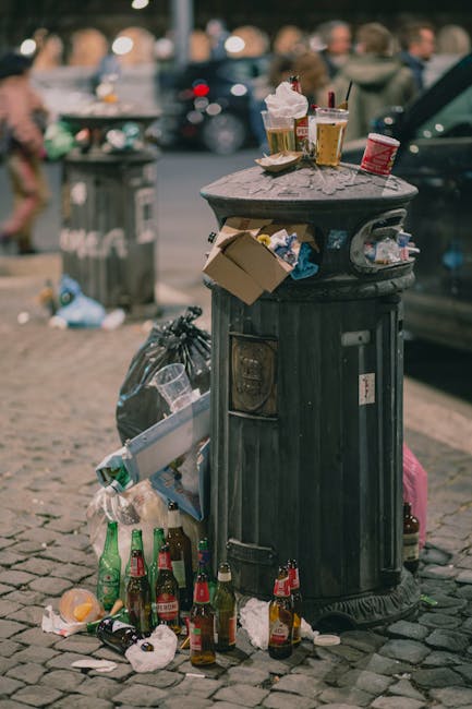 A large outdoor collection of various waste materials, including multiple stacks of empty cardboard boxes labeled with 'fresh fruits' on the sides, positioned on a paved surface in front of a dark bui